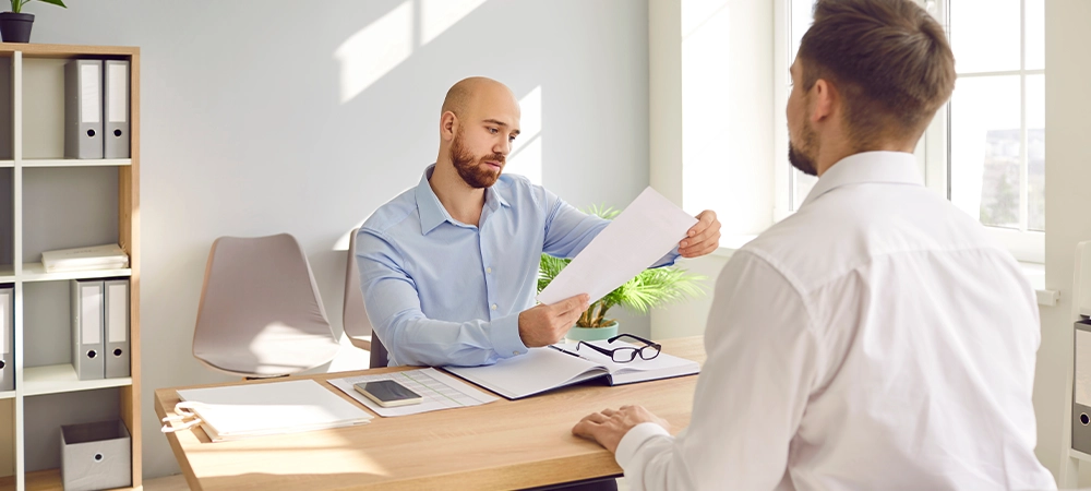 business men and insurance agent sitting at the desk on a meeting. Confident man interviewing new candidate for vacancy company sitting in office holding and reading resume.