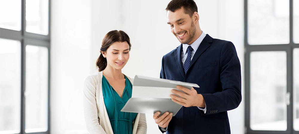 real estate business, sale and people concept - happy smiling realtor with folder showing documents to female customer at new office room