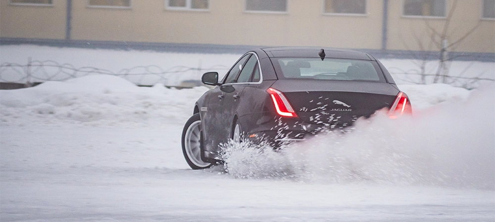 All wheel drive Jaguar XJ skids and drifts on a slippery snow surface at the test-drive event in a winter driving school. Electronic Stability Program is off