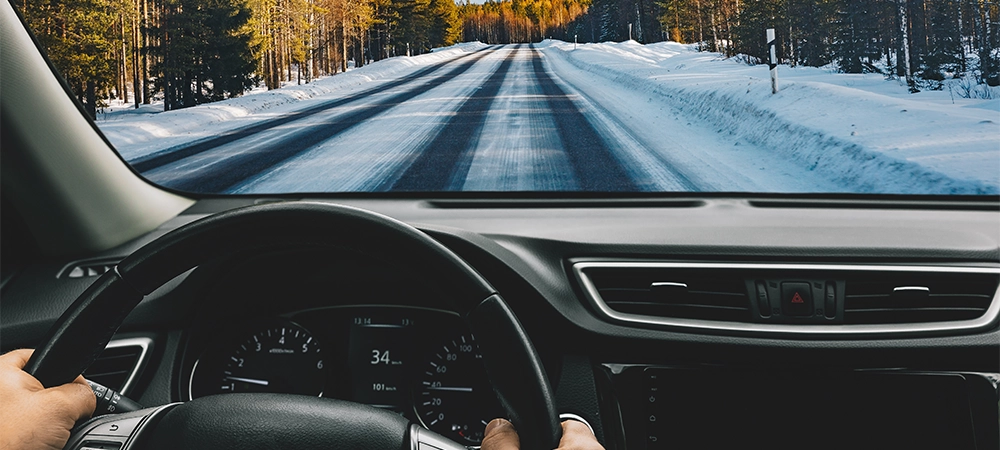 Man driving car on frozen snow country road in winter Finland. Rear view.
