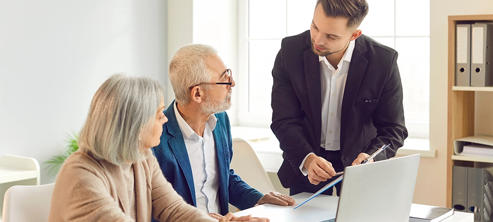 Adviser, agent, or consultant is helping a pair of senior clients with insurance and financial investments during a meeting in the office. Importance of financial planning and insurance for elderly.