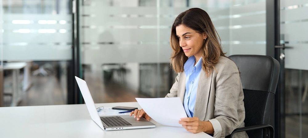 Busy 40 years old business woman entrepreneur working in office checking documents in office. Businesswoman of middle age account manager executive or lawyer using laptop computer at work.