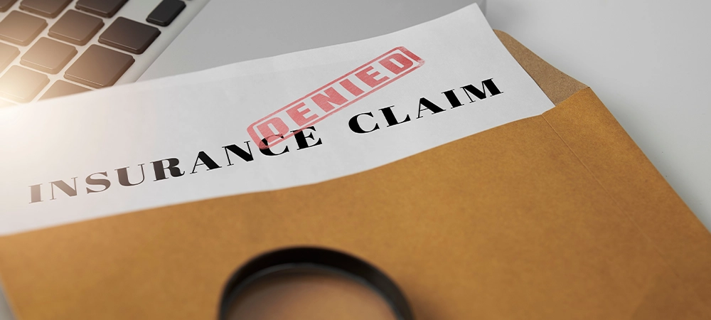 Document with denied stamp and magnifying glasses put on the laptop on white table background.